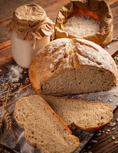 Cut loaf of artisanal wheat bread in a wooden background