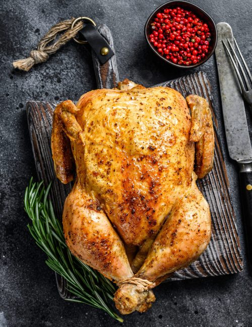 Grilled roasted whole Chicken.  Black background. Top view. Copy space.