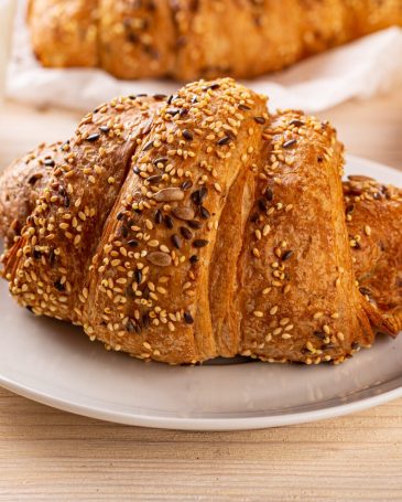 Multigrain croissant sprinkled with seeds served with milk, breakfast idea