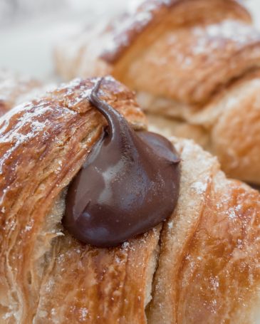 Two fresh italian croissants filled by  chocolate cream. Close-up.